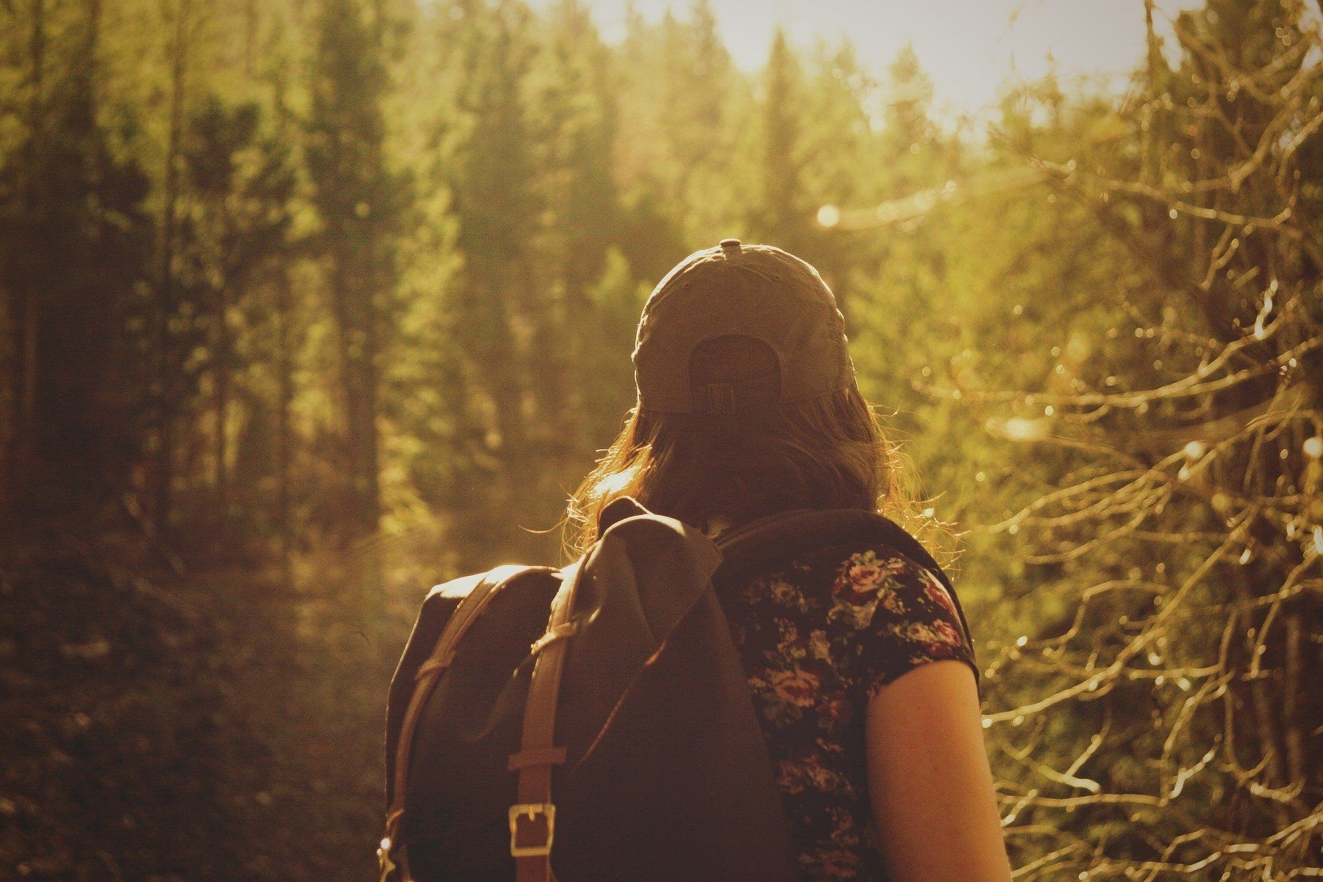 Eine Wanderin steht mit Rucksack im Wald