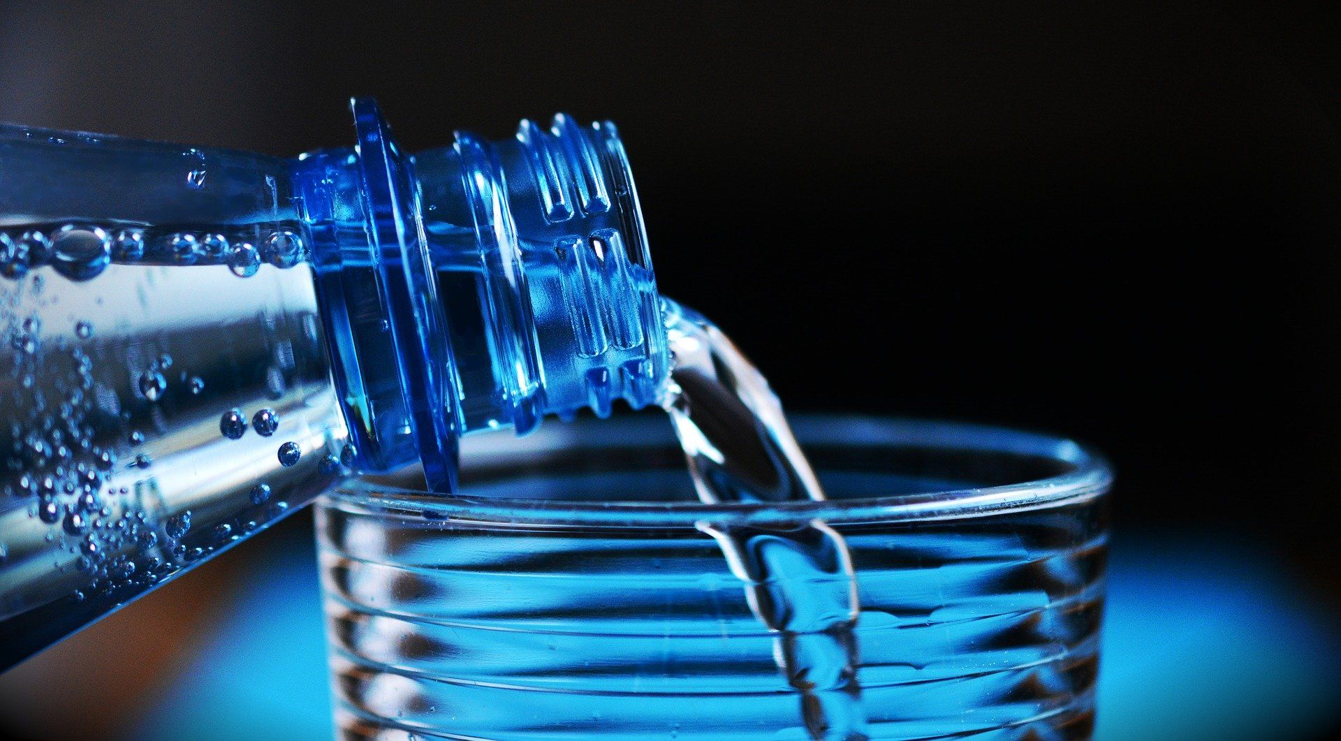 Wasser wird aus einer Flasche in ein Glas eingeschenkt
