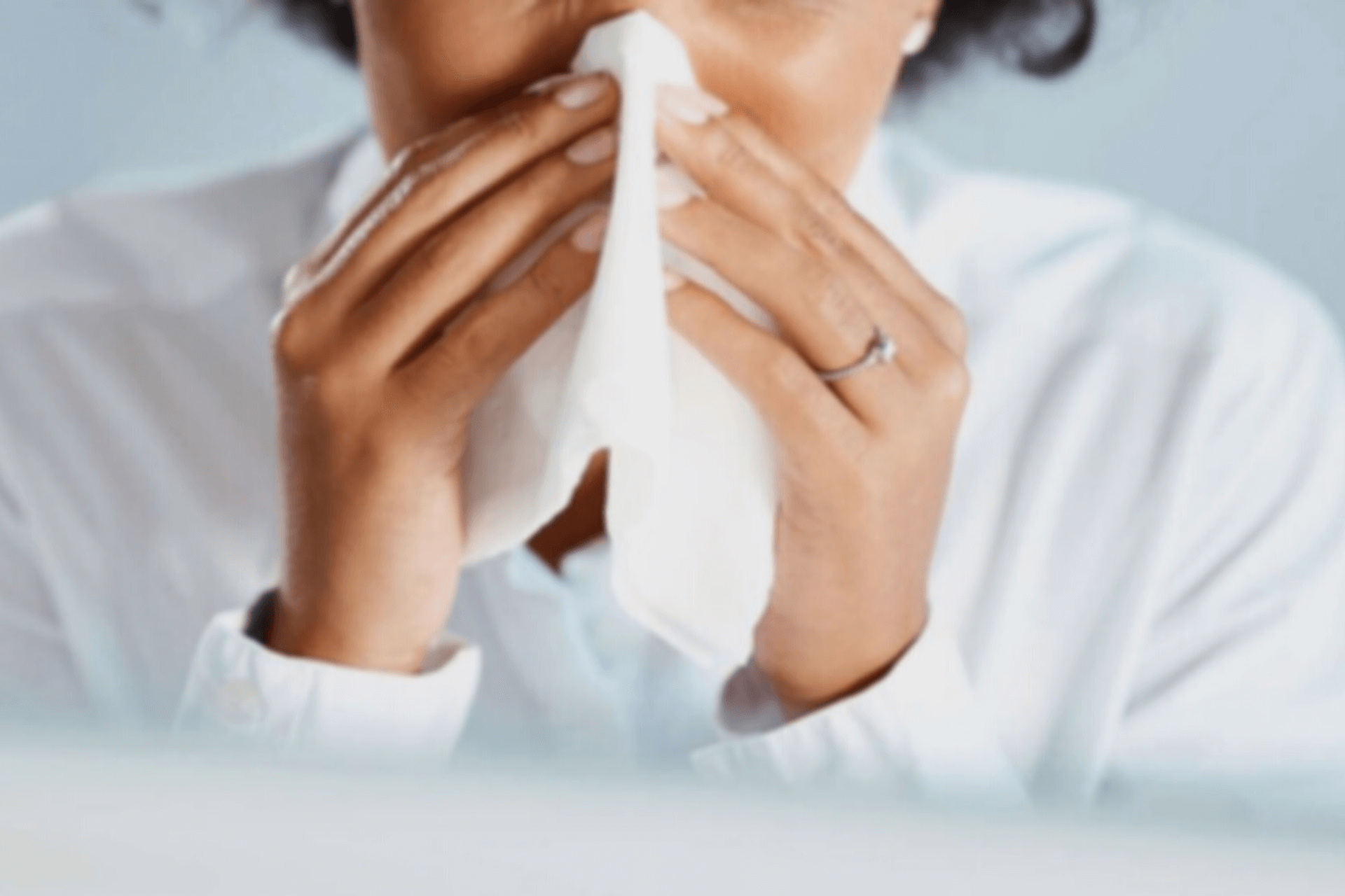 Erkältung: Eine Frau niest ins Taschentuch